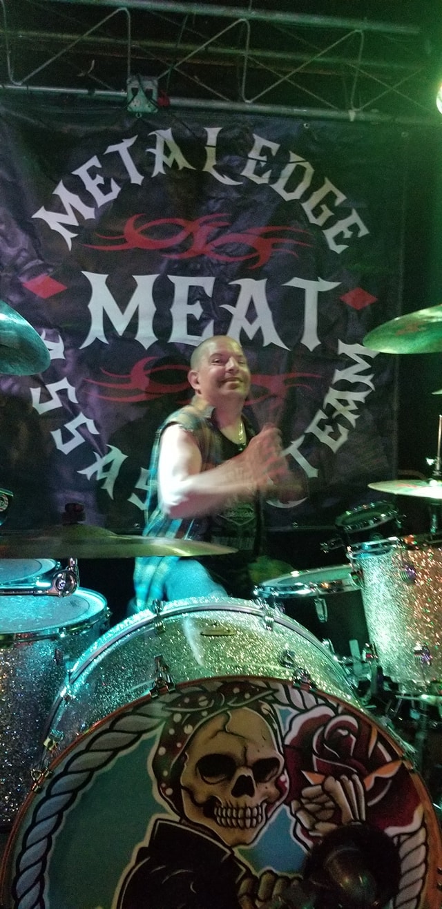 Daniel Jesse performing live with MEAT — silver drum kit, MEAT banner backdrop